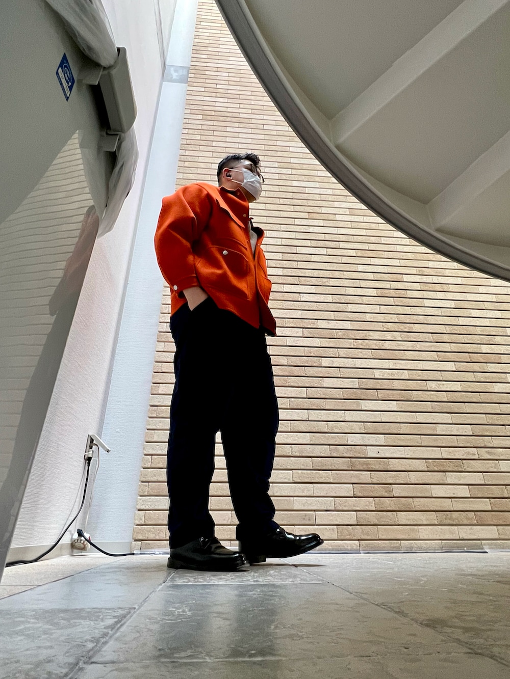 オレンジ系のカバーオール、ブルー系のチノパンツ、ブラック系のドレスシューズを着用したメンズの冬コーディネートの2枚目の写真