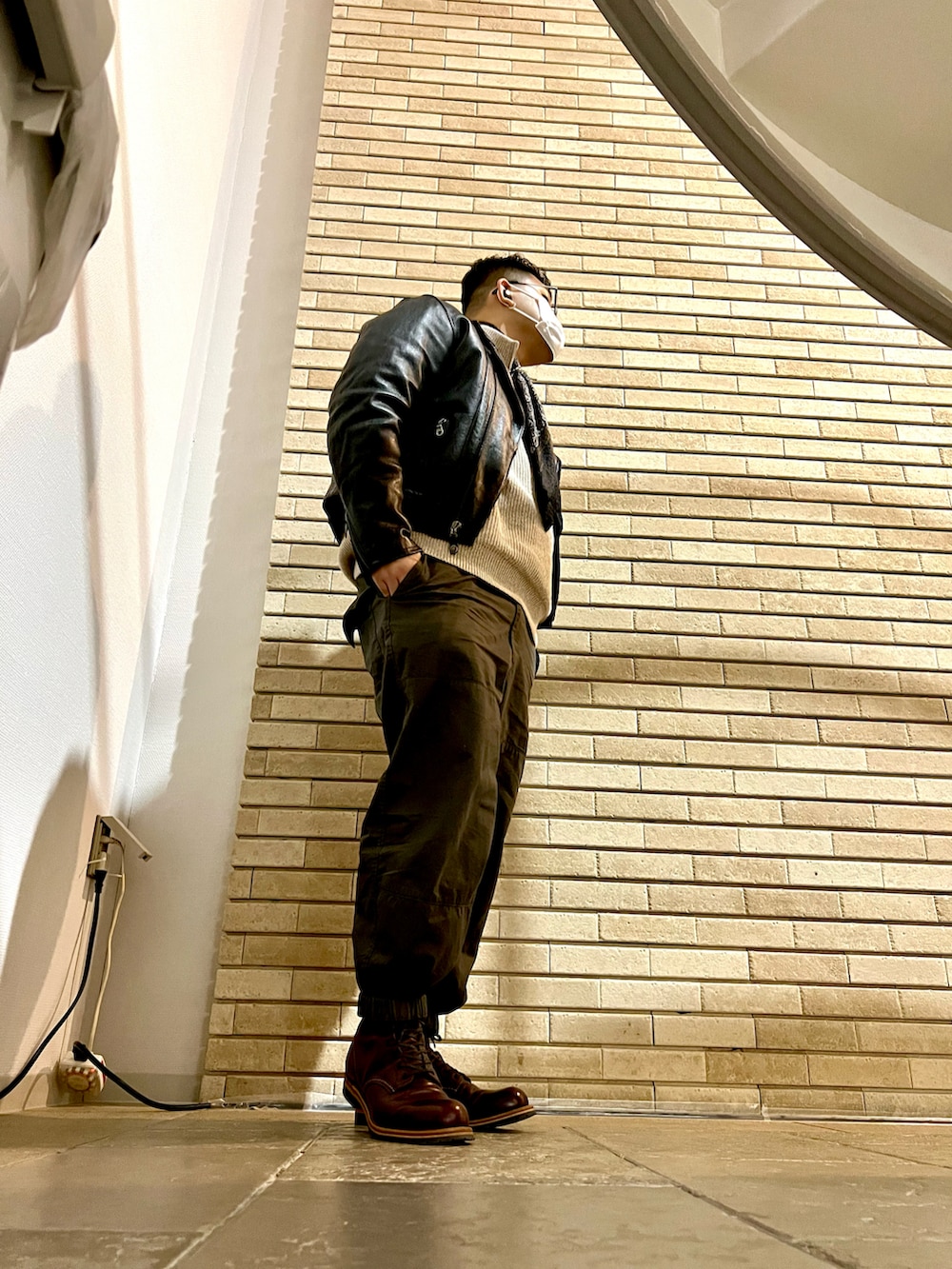 ブラック系のライダースジャケット、グリーン系のその他パンツ、レッド系のブーツを着用したメンズの冬コーディネートの3枚目の写真