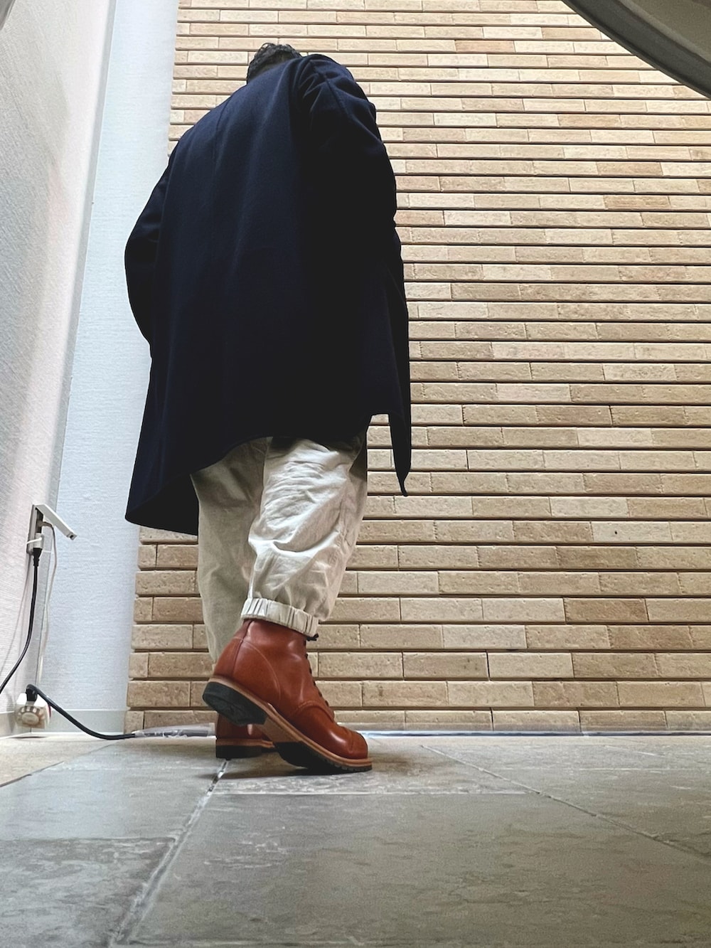 オレンジ系のブーツ、ブルー系のチェスターコート、ホワイト系のその他パンツを着用したメンズの冬コーディネートの2枚目の写真