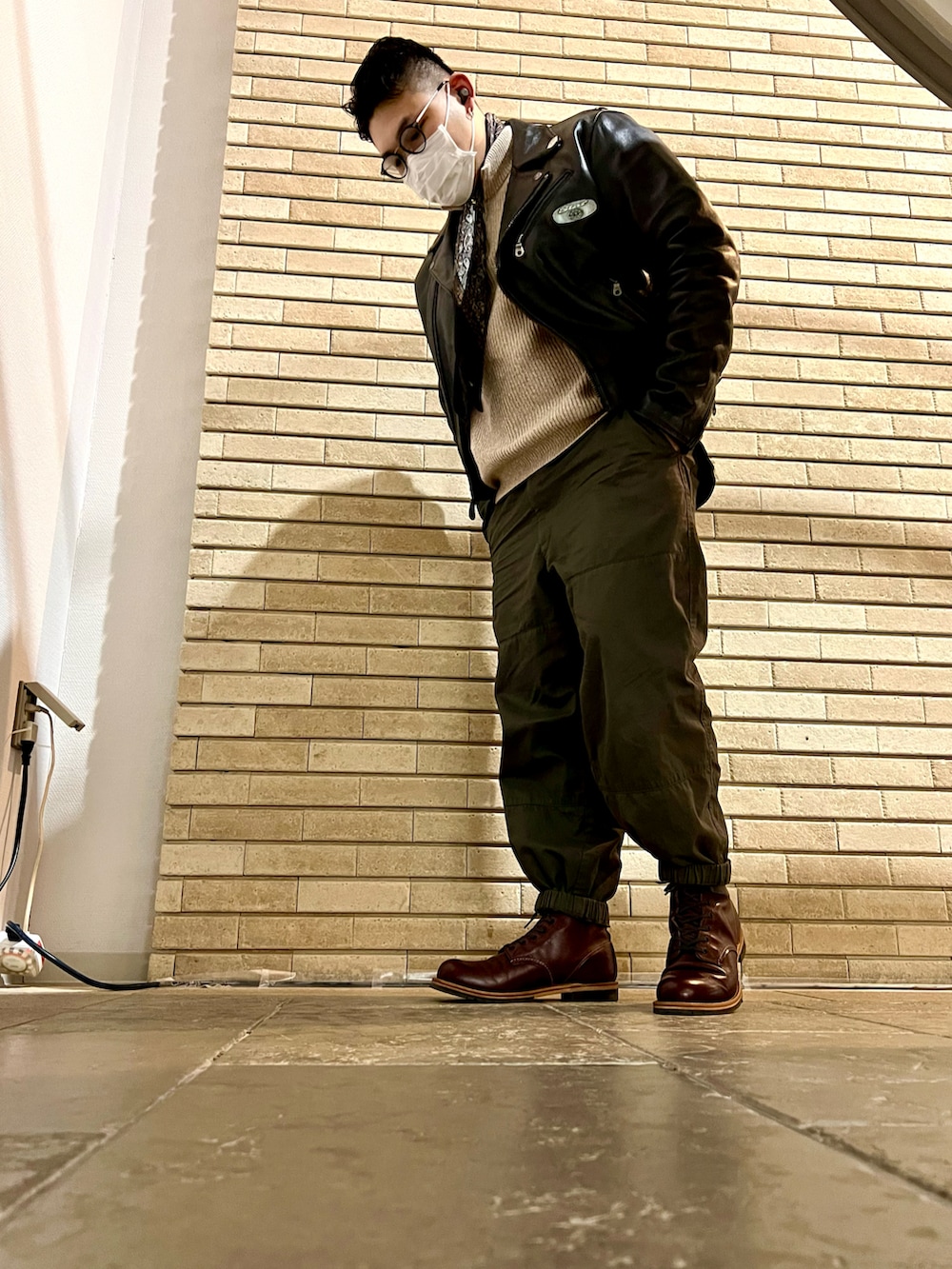 ブラック系のライダースジャケット、グリーン系のその他パンツ、レッド系のブーツを着用したメンズの冬コーディネートの2枚目の写真