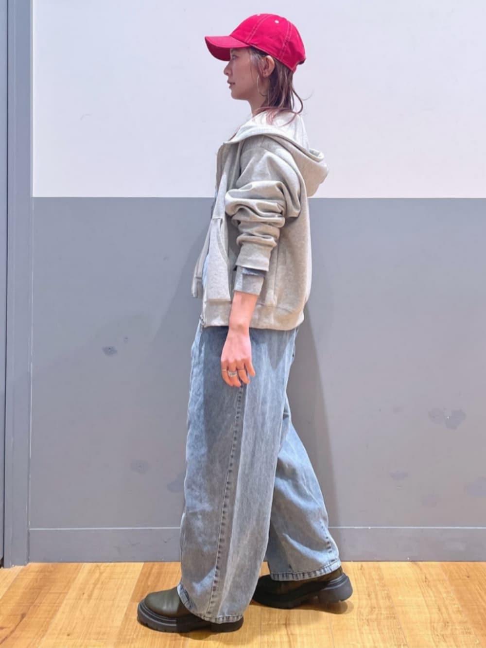グレー系のパーカー、ブルー系のサロペット/オーバーオール、レッド系のキャップを着用したレディースの春コーディネートの4枚目の写真