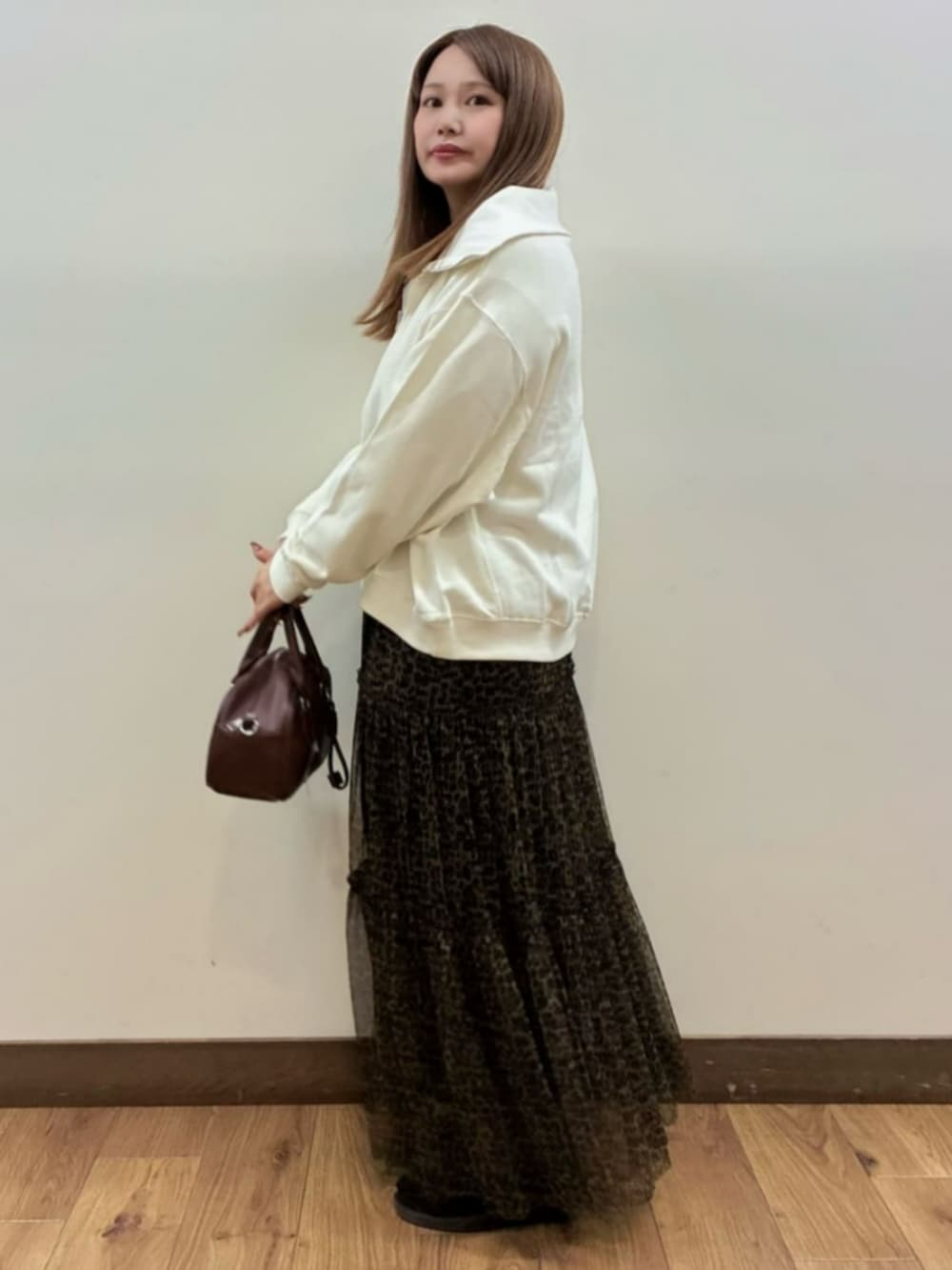 ブラウン系のショルダーバッグ、ホワイト系のスウェット、ブラウン系のスカートを着用したレディースの秋コーディネートの2枚目の写真