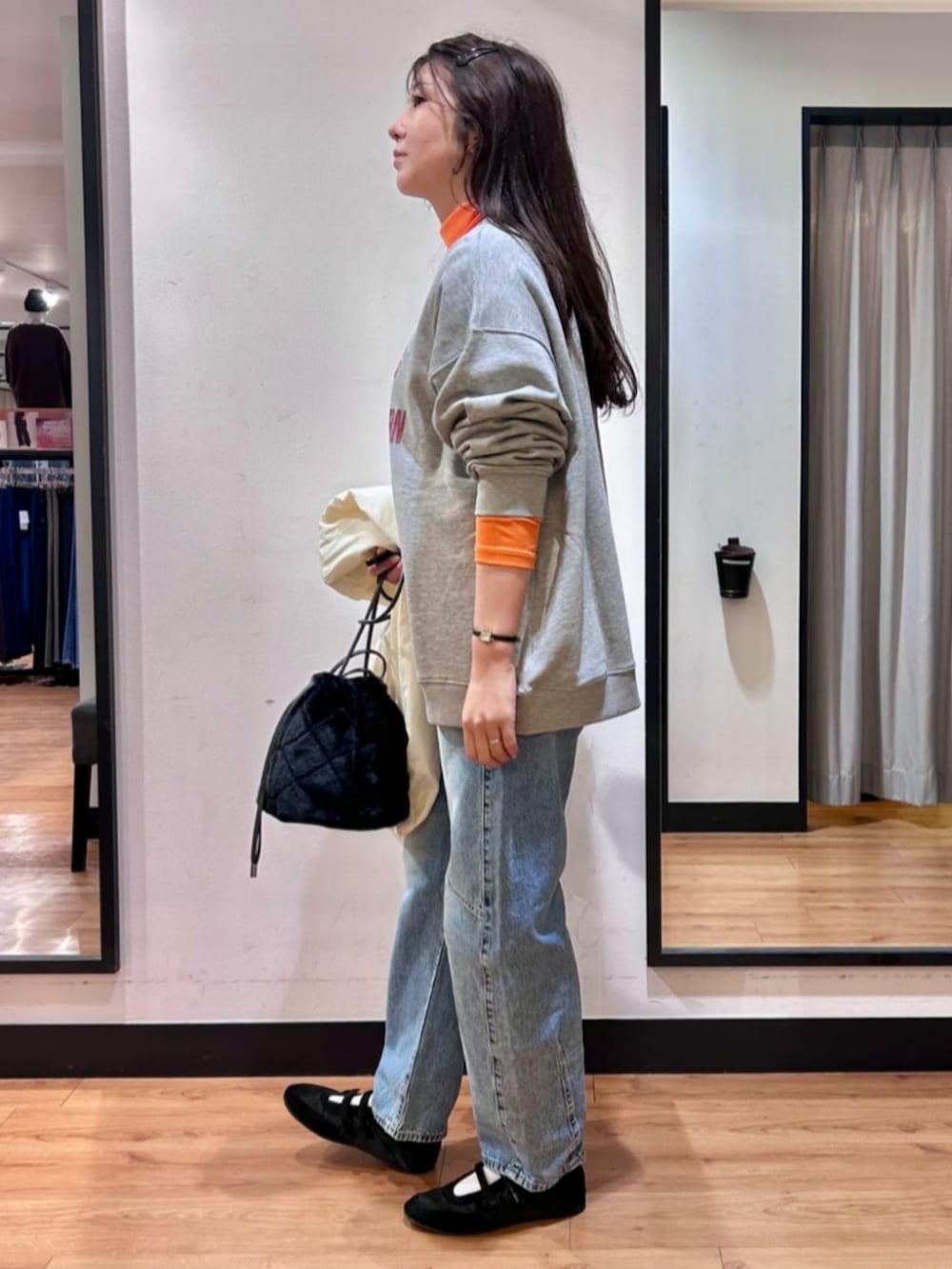 グレー系のスウェット、ブラック系のショルダーバッグ、ブルー系のデニムパンツを着用したレディースの冬コーディネートの2枚目の写真