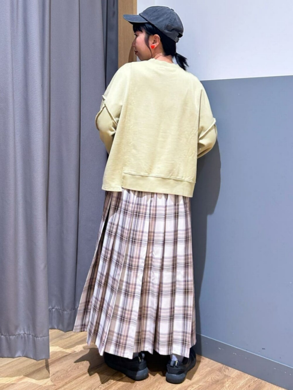 グリーン系のスウェット、ベージュ系のスカート、ブラック系のキャップを着用したレディースの秋コーディネートの3枚目の写真