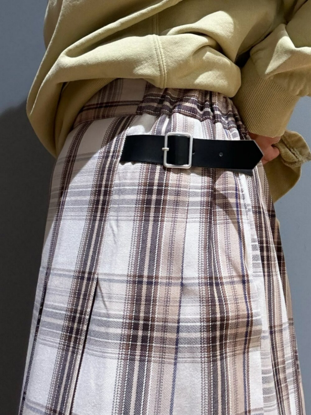 グリーン系のスウェット、ベージュ系のスカート、ブラック系のキャップを着用したレディースの秋コーディネートの7枚目の写真