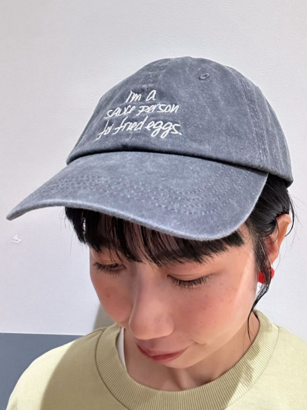 グリーン系のスウェット、ベージュ系のスカート、ブラック系のキャップを着用したレディースの秋コーディネートの8枚目の写真