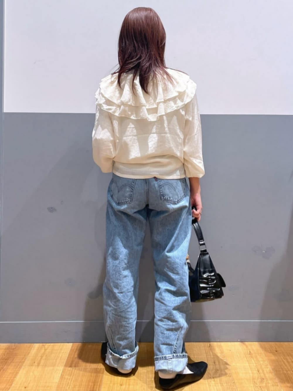 ブラック系のショルダーバッグ、ホワイト系のTシャツ/カットソー、ブルー系のデニムパンツを着用したレディースの秋コーディネートの3枚目の写真