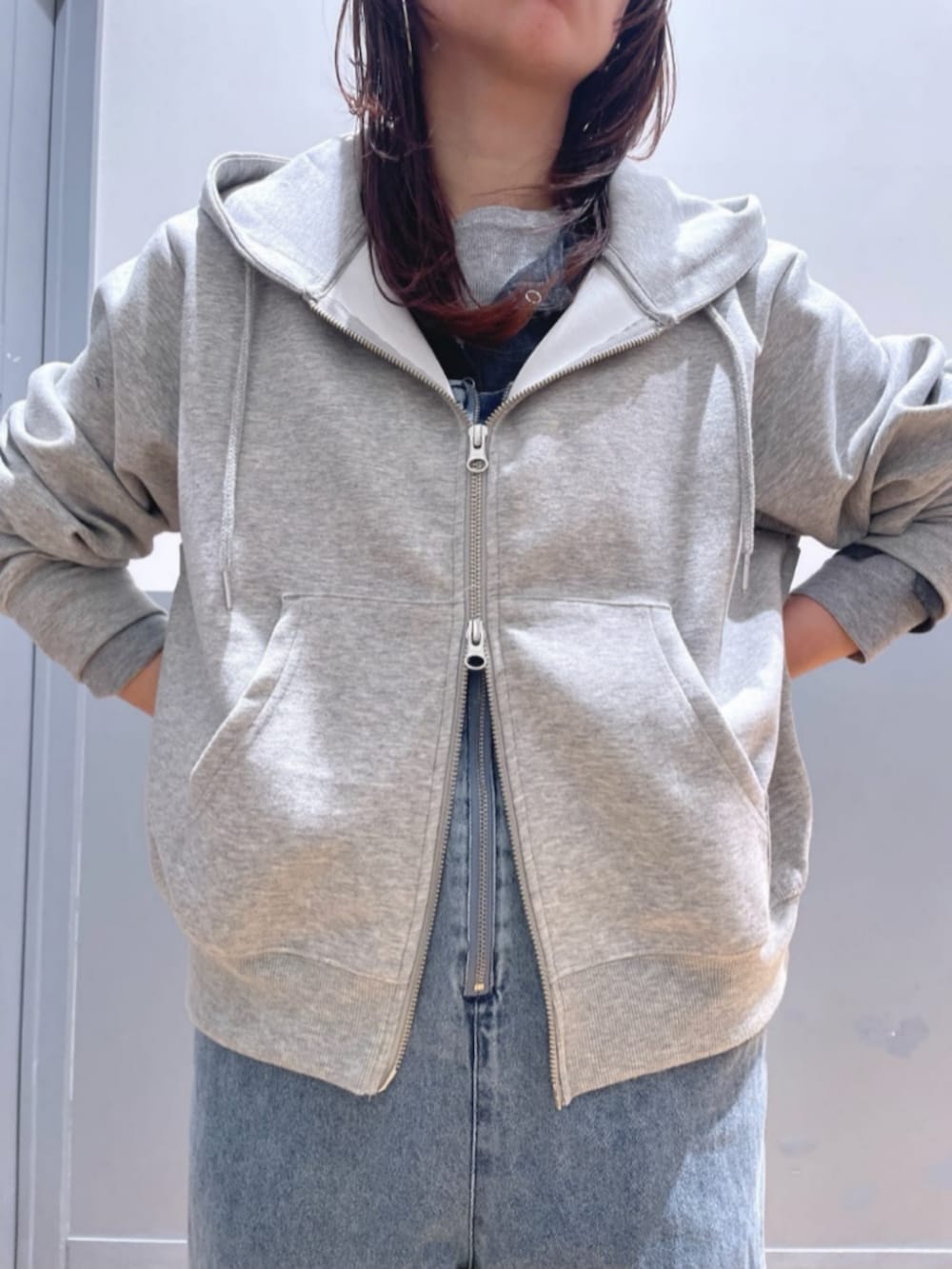 グレー系のパーカー、ブルー系のサロペット/オーバーオール、レッド系のキャップを着用したレディースの春コーディネートの7枚目の写真