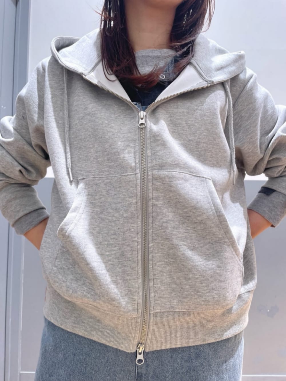 グレー系のパーカー、ブルー系のサロペット/オーバーオール、レッド系のキャップを着用したレディースの春コーディネートの6枚目の写真