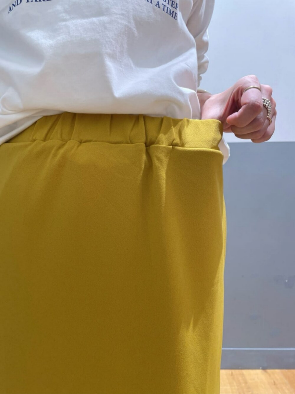 イエロー系のスカート、ホワイト系のTシャツ/カットソー、グレー系のその他トップスを着用したレディースの秋コーディネートの8枚目の写真