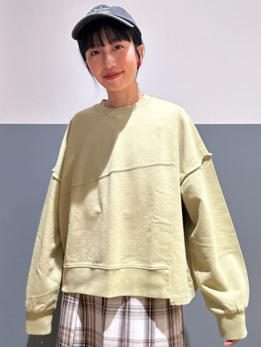 グリーン系のスウェット、ベージュ系のスカート、ブラック系のキャップを着用したレディースの秋コーディネートの4枚目の写真