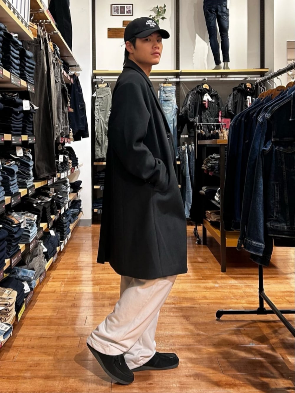 グレー系のその他パンツ、ブルー系のニット/セーター、ブラック系のチェスターコートを着用したメンズの秋コーディネートの2枚目の写真