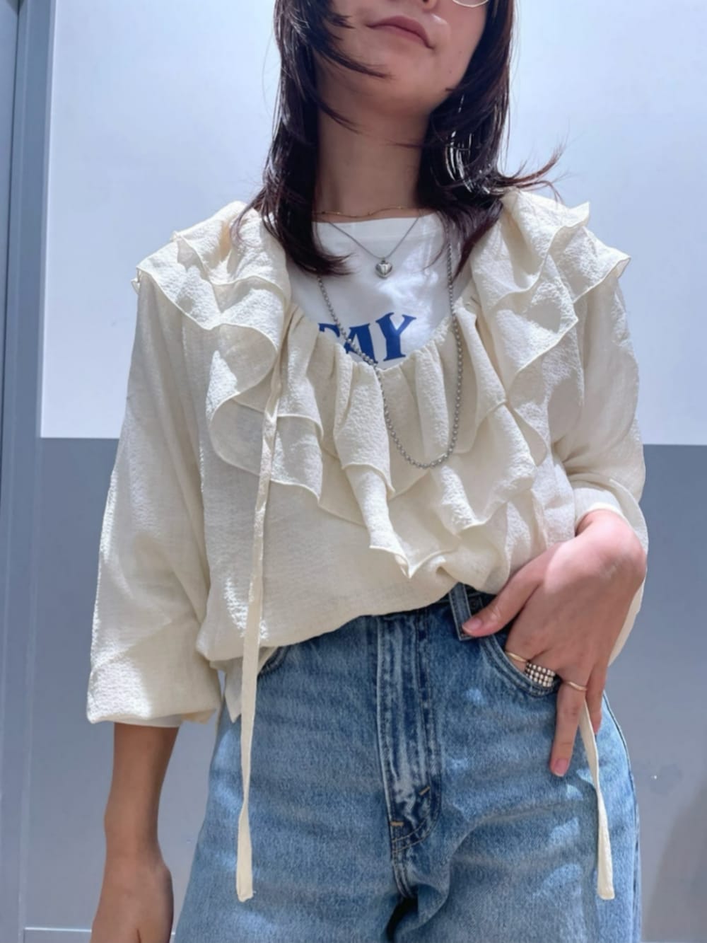 ブラック系のショルダーバッグ、ホワイト系のTシャツ/カットソー、ブルー系のデニムパンツを着用したレディースの秋コーディネートの5枚目の写真