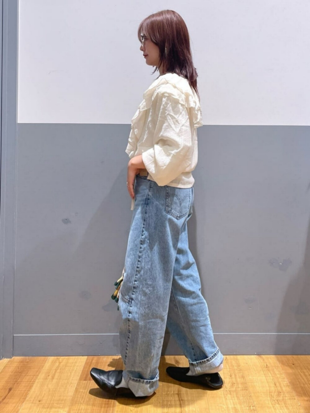 ブラック系のショルダーバッグ、ホワイト系のTシャツ/カットソー、ブルー系のデニムパンツを着用したレディースの秋コーディネートの4枚目の写真