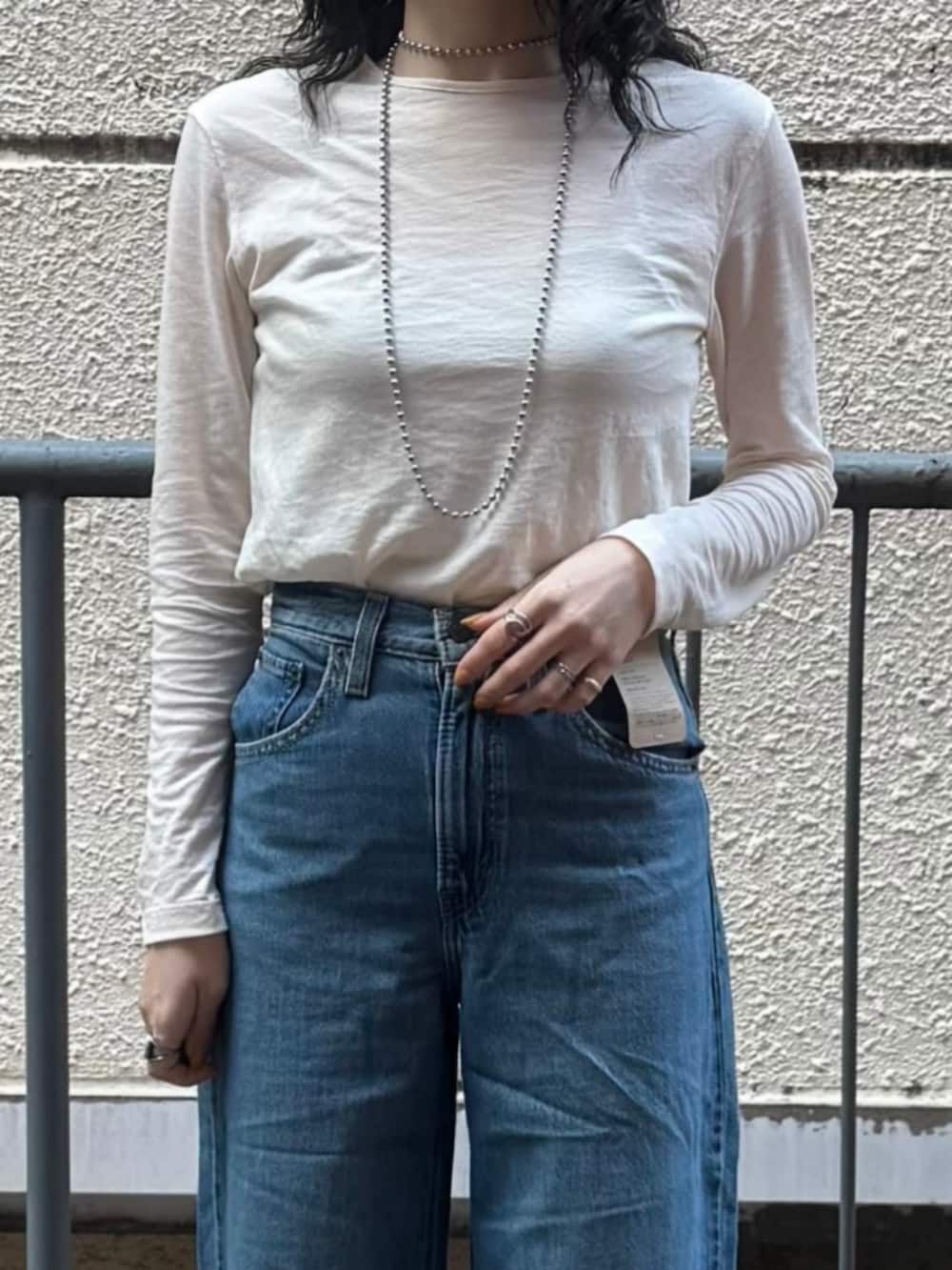 ホワイト系のTシャツ/カットソー、イエロー系のニット/セーター、ブルー系のデニムパンツを着用したレディースの春コーディネートの8枚目の写真