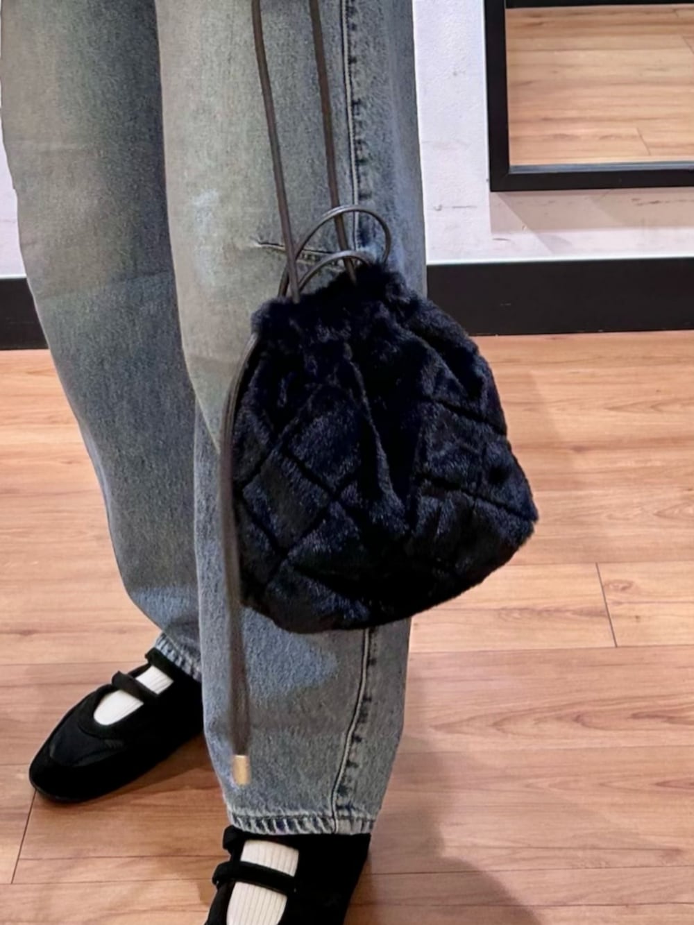 グレー系のスウェット、ブラック系のショルダーバッグ、ブルー系のデニムパンツを着用したレディースの冬コーディネートの10枚目の写真