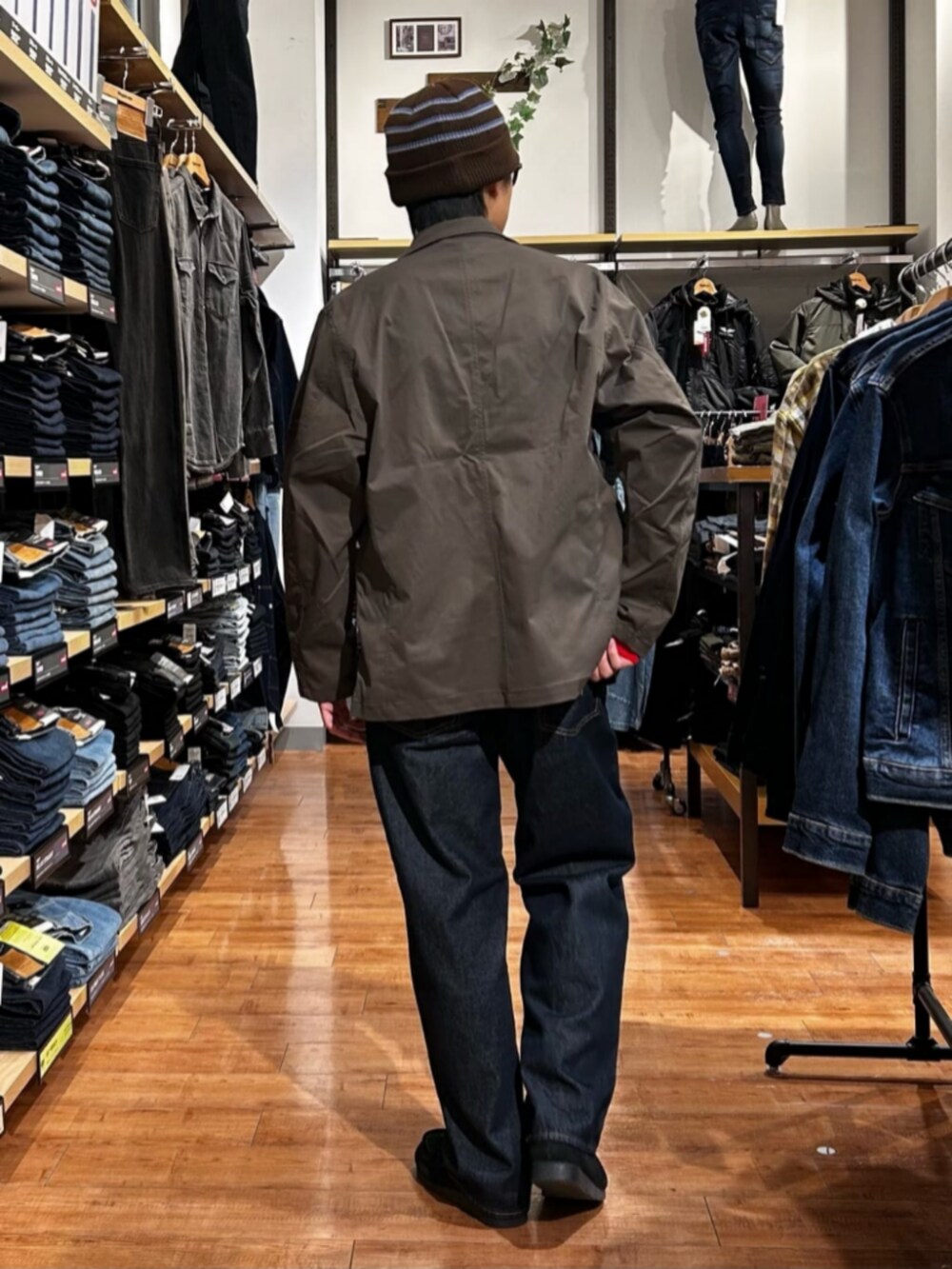 ブルー系のデニムパンツ、レッド系のニット/セーター、ブラウン系のテーラードジャケットを着用したメンズの冬コーディネートの4枚目の写真