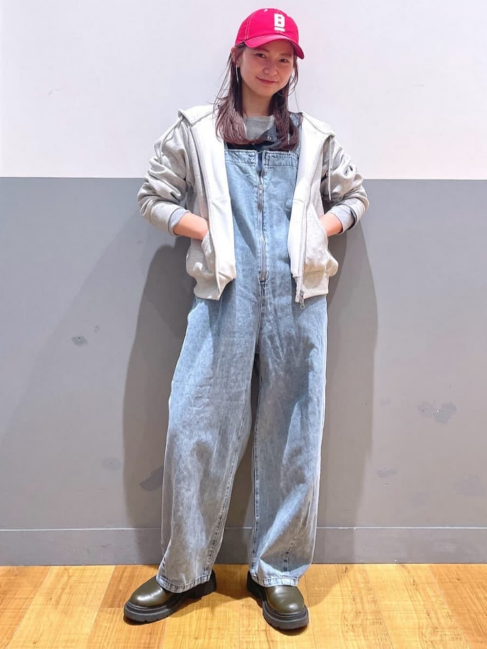 グレー系のパーカー、ブルー系のサロペット/オーバーオール、レッド系のキャップを着用したレディースの春コーディネートの5枚目の写真