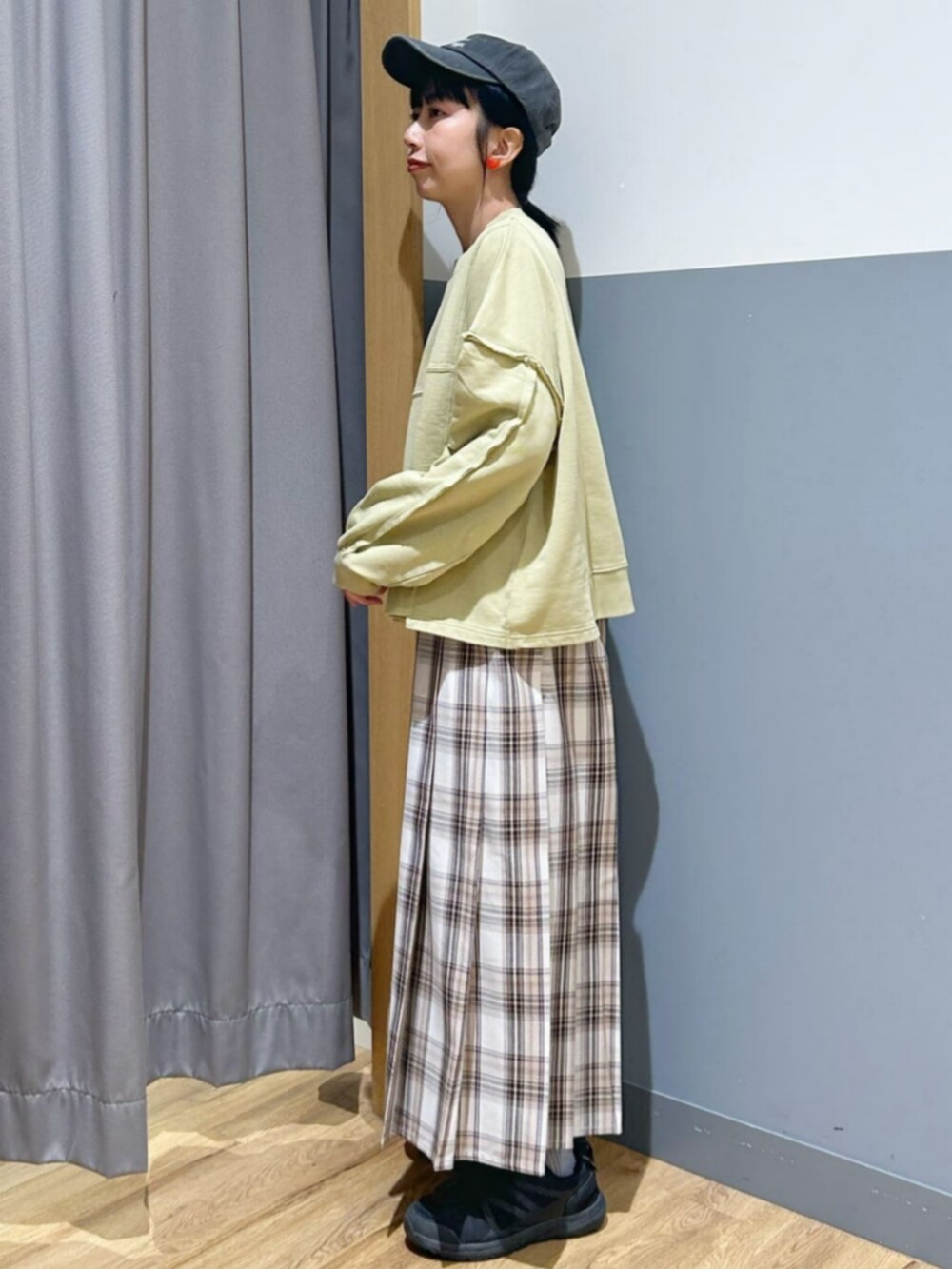 グリーン系のスウェット、ベージュ系のスカート、ブラック系のキャップを着用したレディースの秋コーディネートの2枚目の写真