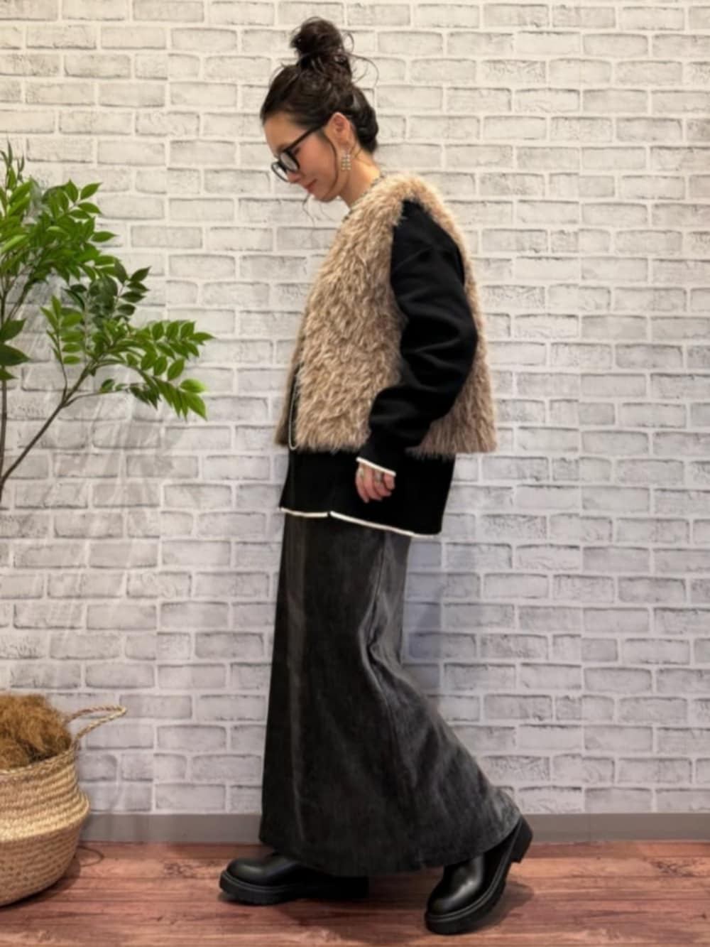 グレー系のスカート、ブラウン系のベスト、ブラック系のニット/セーターを着用したレディースの秋コーディネートの2枚目の写真