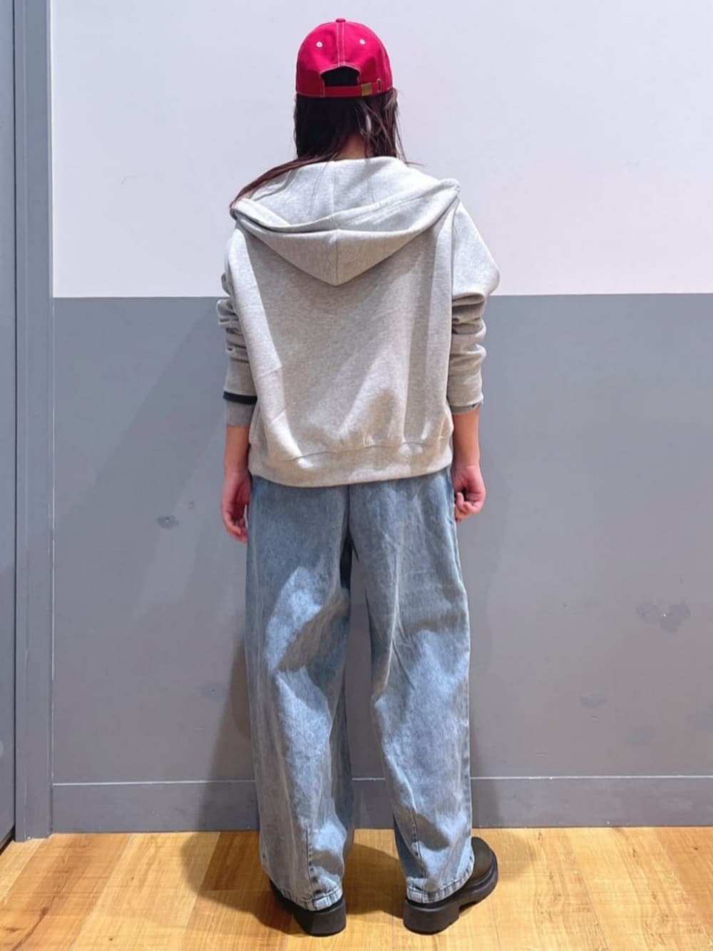 グレー系のパーカー、ブルー系のサロペット/オーバーオール、レッド系のキャップを着用したレディースの春コーディネートの3枚目の写真