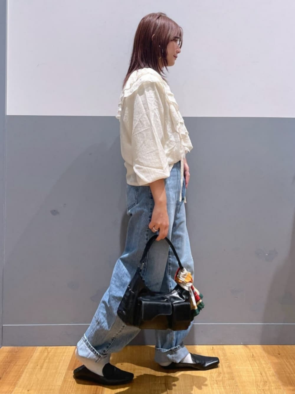 ブラック系のショルダーバッグ、ホワイト系のTシャツ/カットソー、ブルー系のデニムパンツを着用したレディースの秋コーディネートの2枚目の写真