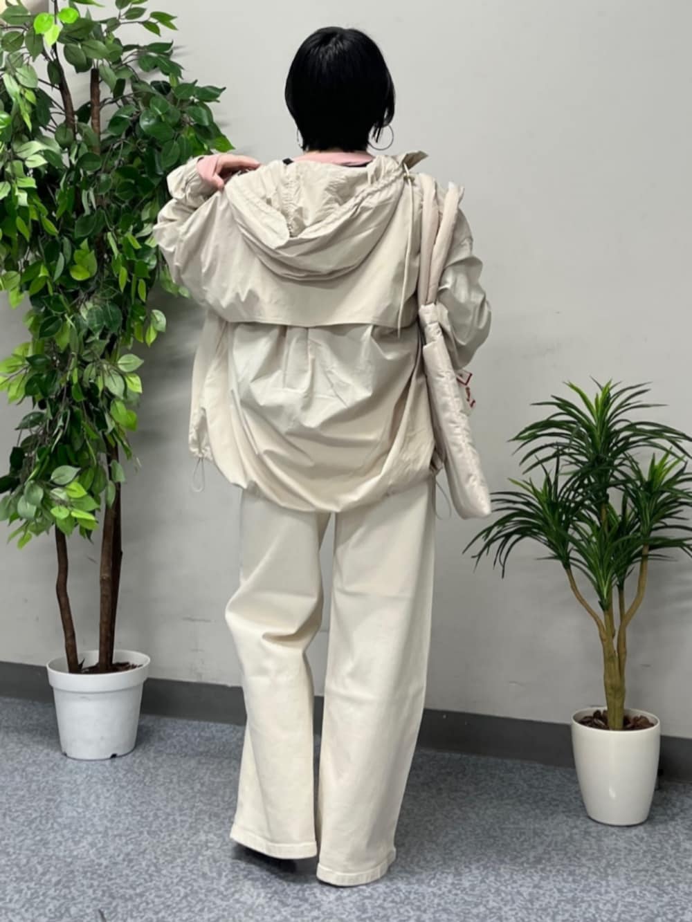 ホワイト系のトートバッグ、ベージュ系のマウンテンパーカー、ホワイト系のデニムパンツを着用したレディースの春コーディネートの3枚目の写真