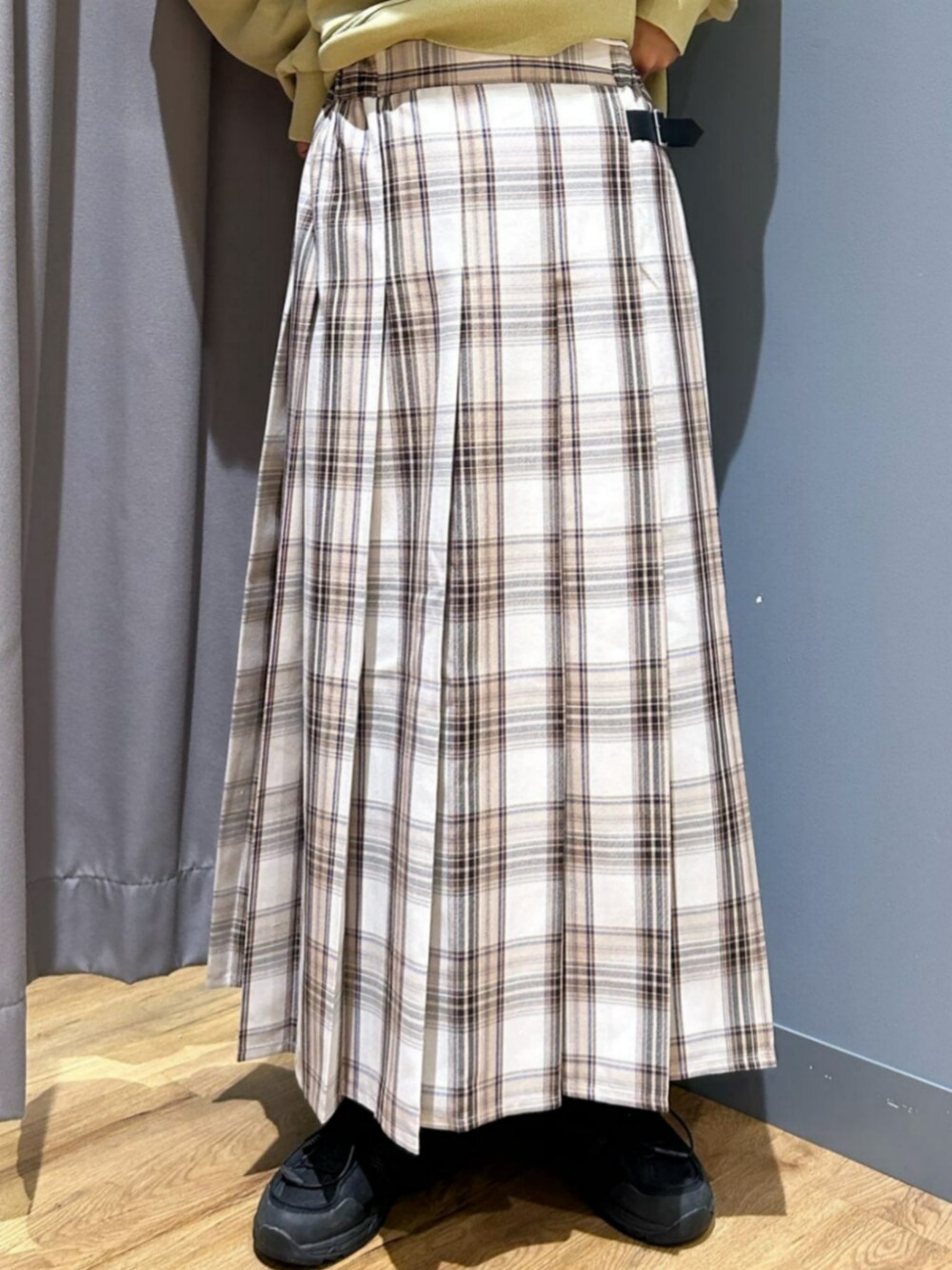 グリーン系のスウェット、ベージュ系のスカート、ブラック系のキャップを着用したレディースの秋コーディネートの6枚目の写真