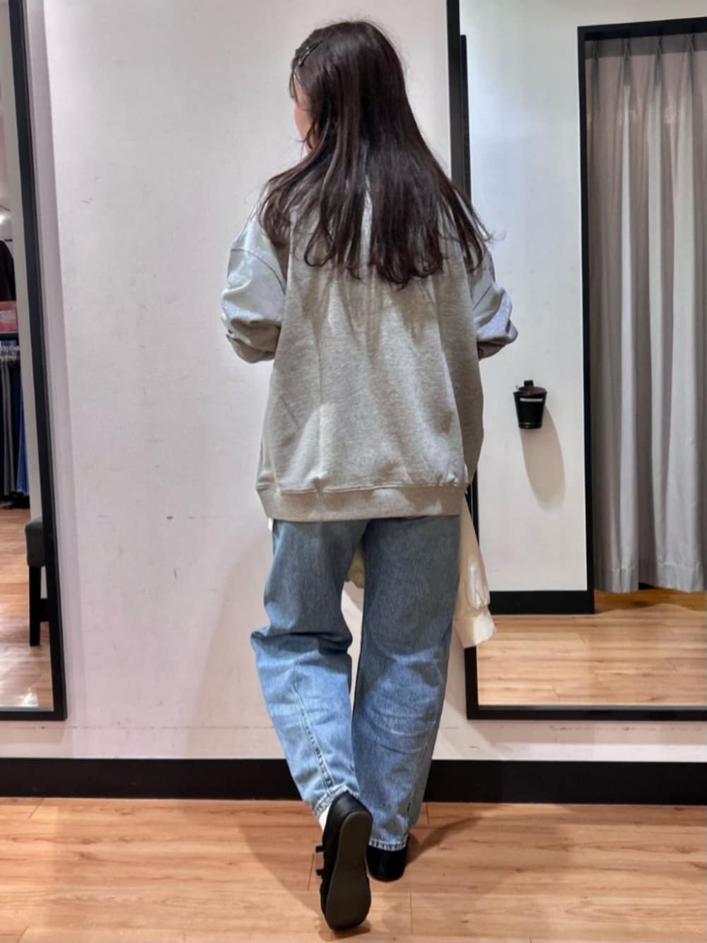 グレー系のスウェット、ブラック系のショルダーバッグ、ブルー系のデニムパンツを着用したレディースの冬コーディネートの3枚目の写真