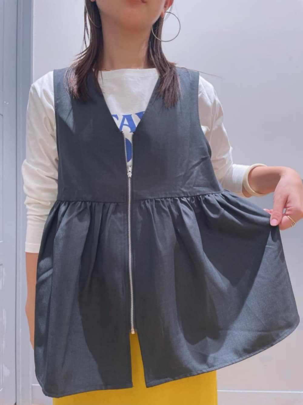 イエロー系のスカート、ホワイト系のTシャツ/カットソー、グレー系のその他トップスを着用したレディースの秋コーディネートの5枚目の写真