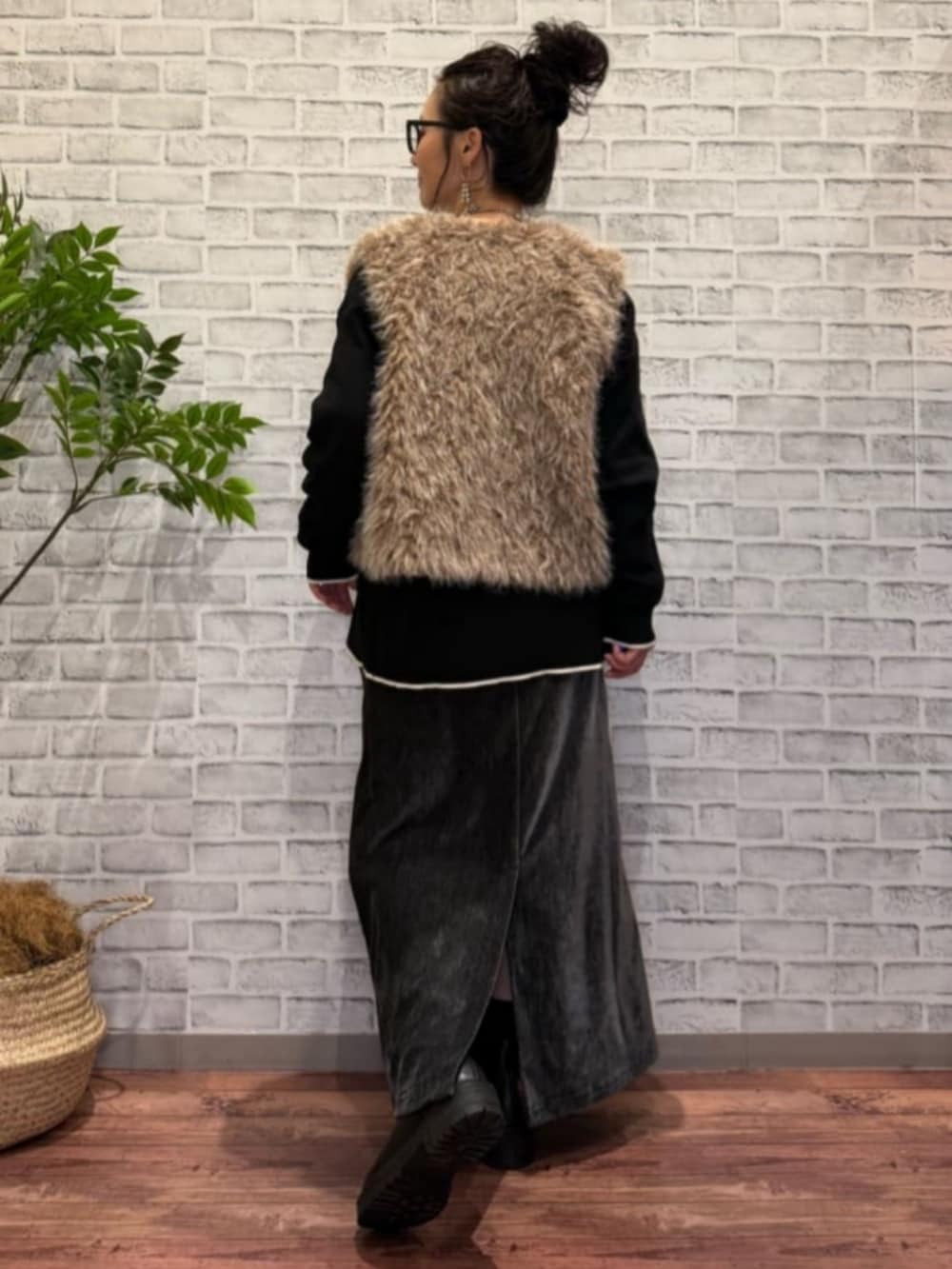 グレー系のスカート、ブラウン系のベスト、ブラック系のニット/セーターを着用したレディースの秋コーディネートの3枚目の写真