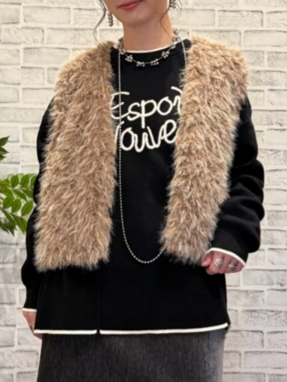 グレー系のスカート、ブラウン系のベスト、ブラック系のニット/セーターを着用したレディースの秋コーディネートの4枚目の写真