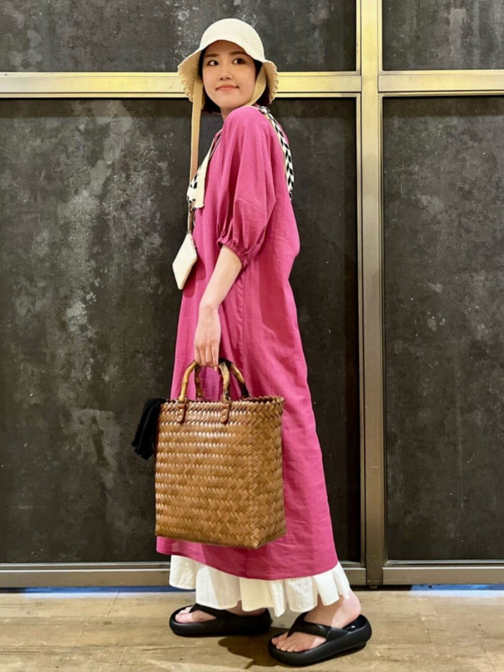 ブラック系のサンダル、ピンク系のシャツワンピース、ホワイト系のスカートを着用したレディースの夏コーディネートの2枚目の写真