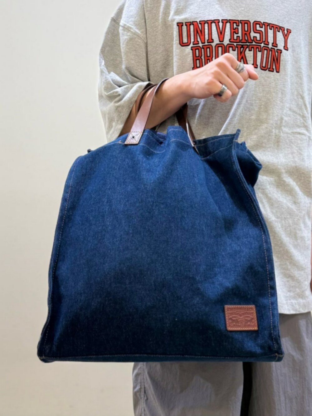 ブルー系のトートバッグ、ホワイト系のTシャツ/カットソー、ブラック系のカーゴパンツを着用したレディースの夏コーディネートの6枚目の写真