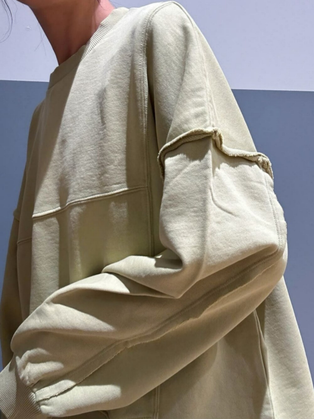 グリーン系のスウェット、ベージュ系のスカート、ブラック系のキャップを着用したレディースの秋コーディネートの5枚目の写真