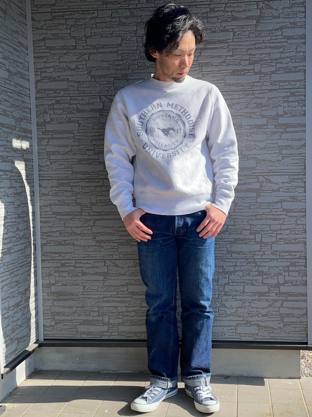 ブルー系のデニムパンツ、グリーン系のミリタリージャケット、ホワイト系のスウェットを着用したメンズの春コーディネートの2枚目の写真