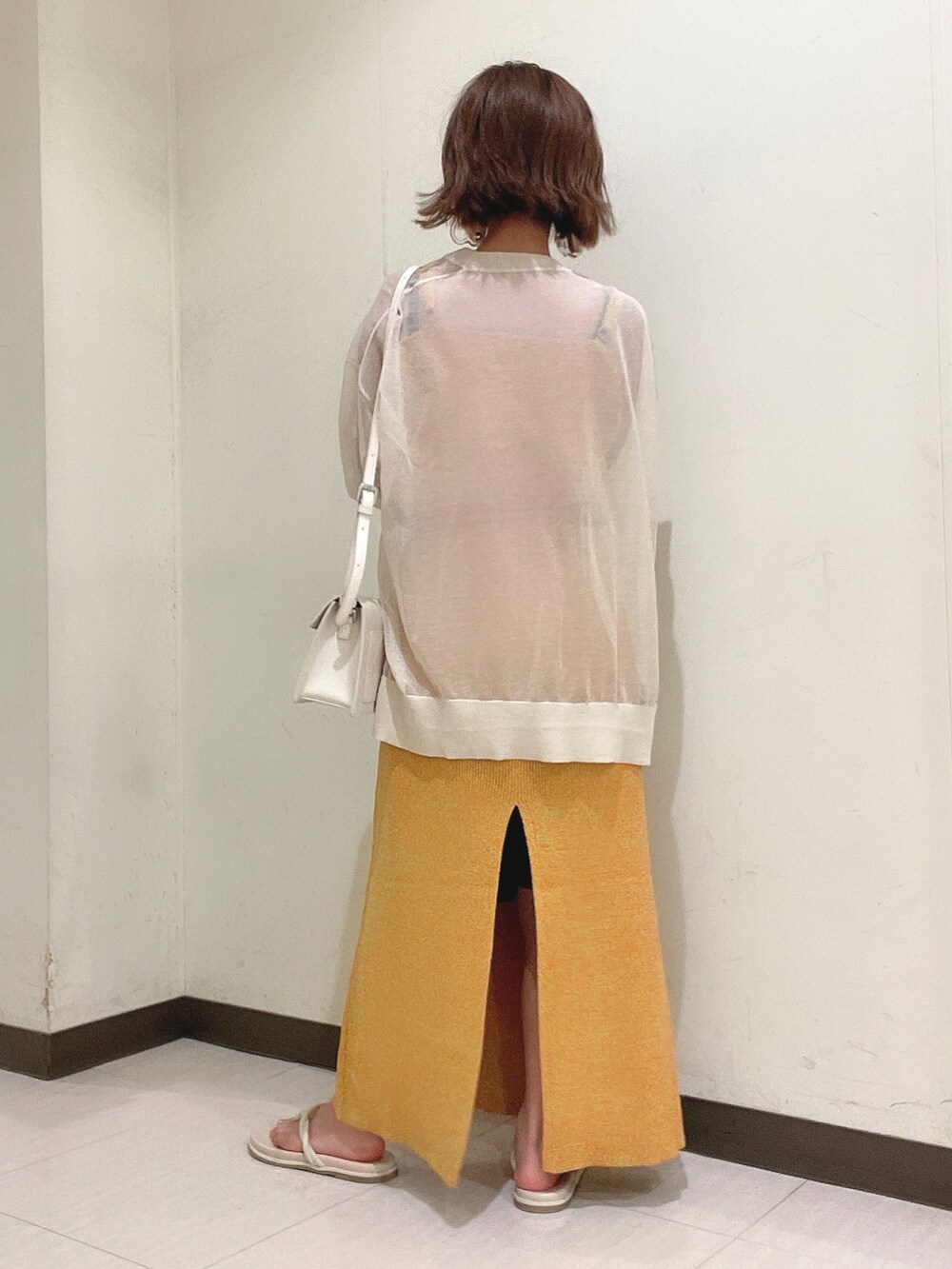 オレンジ系のワンピース、ホワイト系のショルダーバッグ、ベージュ系のカーディガン/ボレロを着用したレディースの夏コーディネートの4枚目の写真