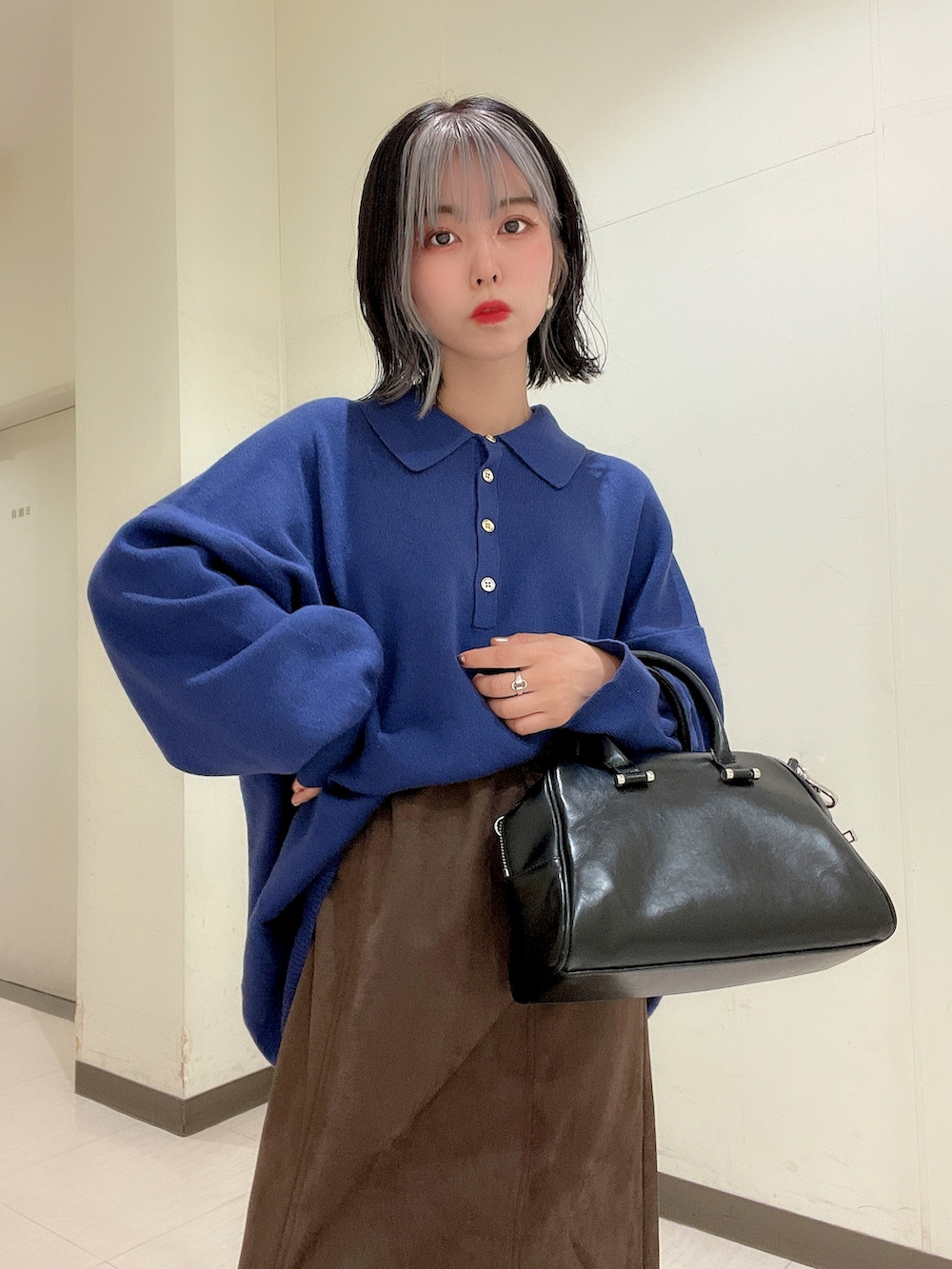 ブルー系のニット/セーター、ブラウン系のスカート、ブラック系のボストンバッグを着用したレディースの秋コーディネートの5枚目の写真