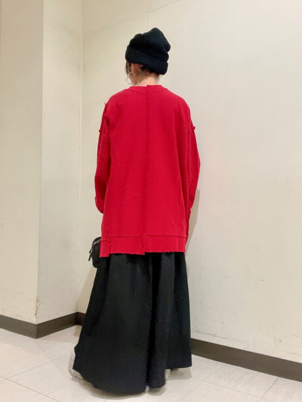 レッド系のスウェット、ブラック系のバッグ、ホワイト系のスカートを着用したレディースの秋コーディネートの4枚目の写真