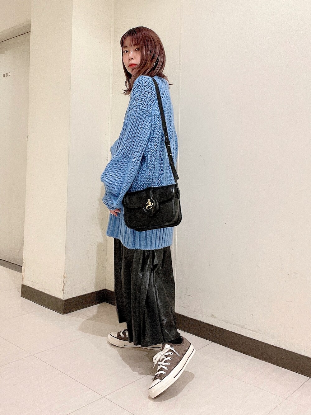 ブルー系のニット/セーター、ブラック系のショルダーバッグ、ブラック系のスカートを着用したレディースの秋コーディネートの2枚目の写真