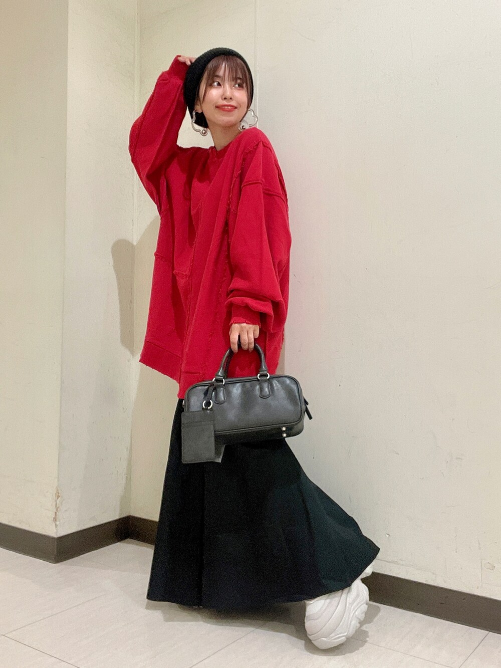 レッド系のスウェット、ブラック系のバッグ、ホワイト系のスカートを着用したレディースの秋コーディネートの2枚目の写真
