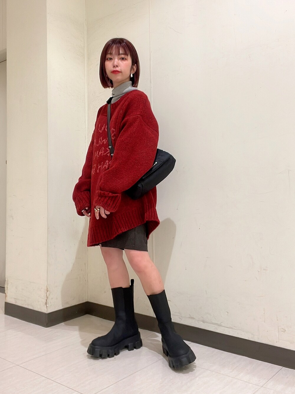 レッド系のニット/セーター、ブラック系のブーツ、ブラック系のショルダーバッグを着用したレディースの冬コーディネートの4枚目の写真