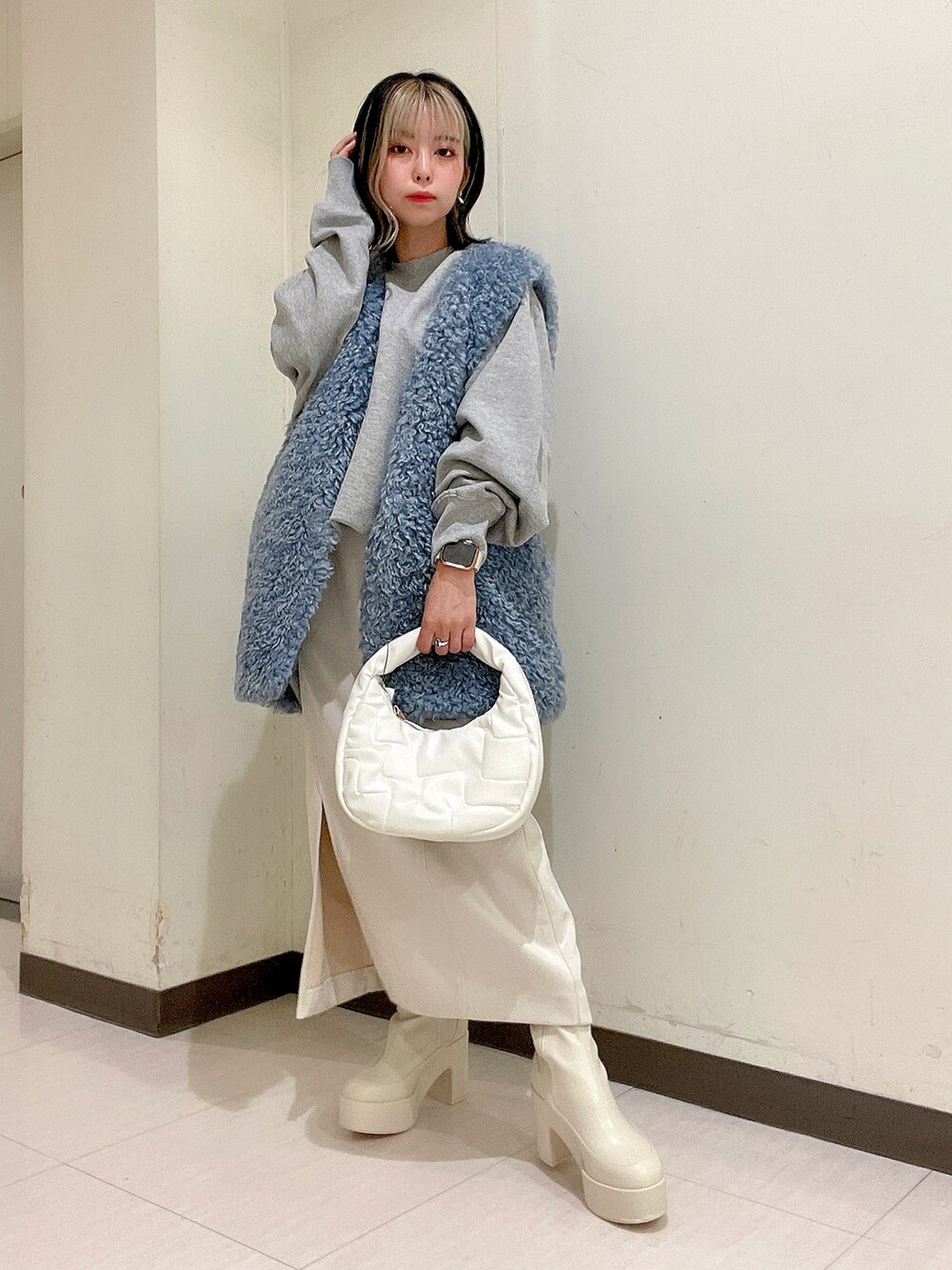ホワイト系のショルダーバッグ、ブルー系のベスト、グレー系のスウェットを着用したレディースの秋コーディネートの3枚目の写真