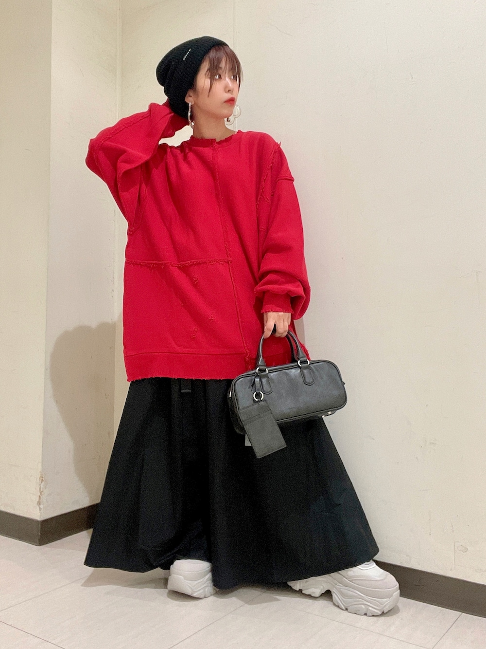 レッド系のスウェット、ブラック系のバッグ、ホワイト系のスカートを着用したレディースの秋コーディネートの5枚目の写真