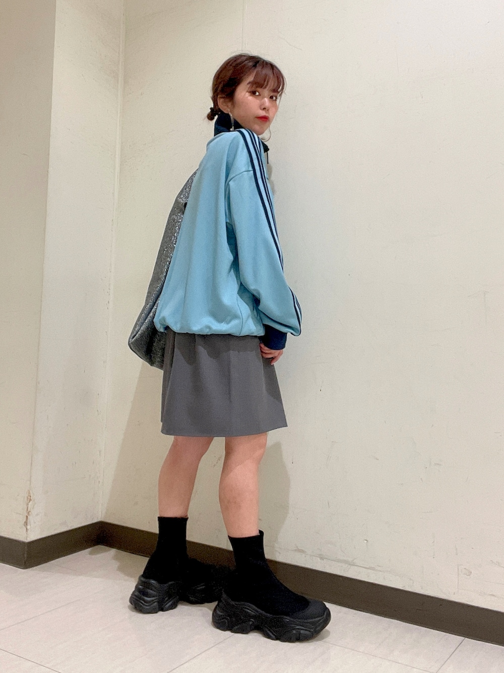 ブルー系のジャージ、シルバー系のトートバッグ、グレー系のスカートを着用したレディースの秋コーディネートの4枚目の写真