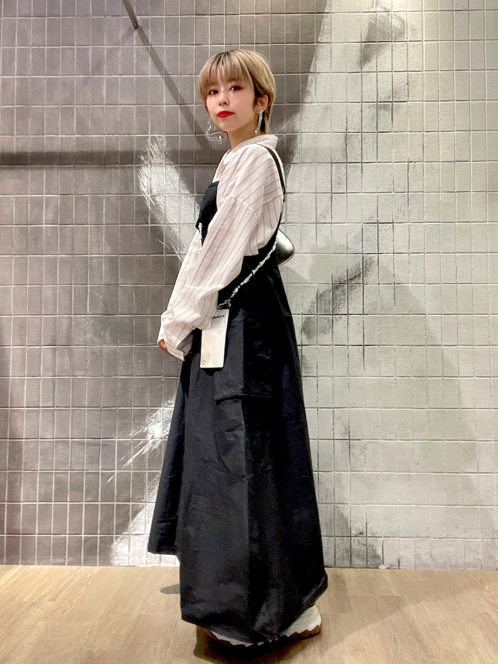 ホワイト系のボストンバッグ、ホワイト系のシャツ/ブラウス、ブラック系のジャンパースカートを着用したレディースの冬コーディネートの2枚目の写真