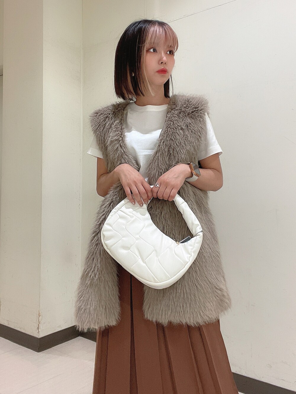 ホワイト系のショルダーバッグ、ブラック系のブーツ、ブラウン系のスカートを着用したレディースの秋コーディネートの4枚目の写真