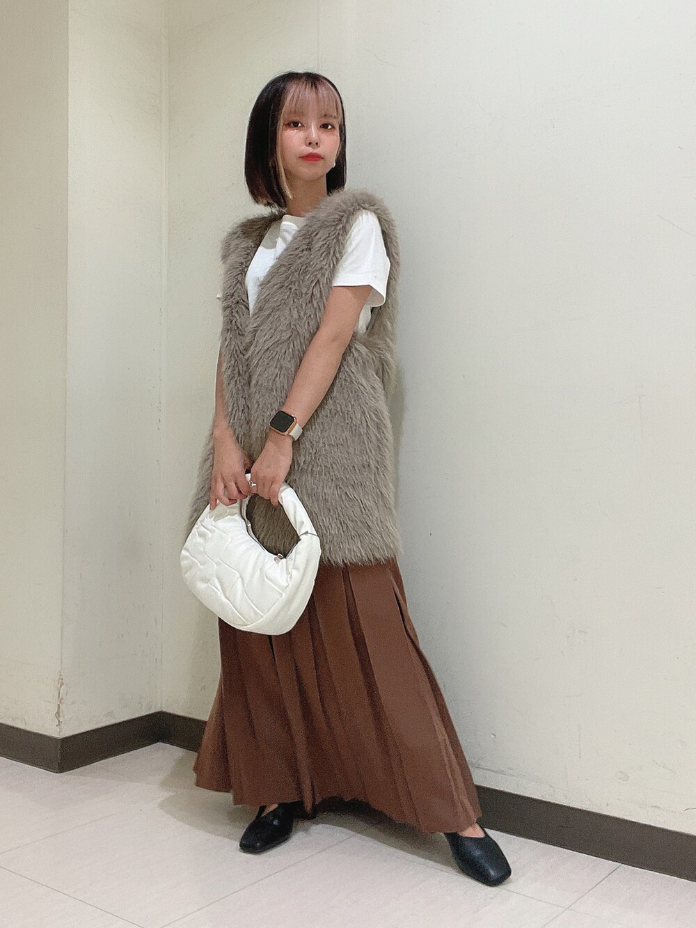 ホワイト系のショルダーバッグ、ブラック系のブーツ、ブラウン系のスカートを着用したレディースの秋コーディネートの3枚目の写真