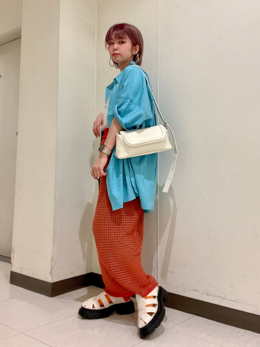 オレンジ系のスカート、ブルー系のシャツ/ブラウス、ホワイト系のショルダーバッグを着用したレディースの春コーディネートの2枚目の写真