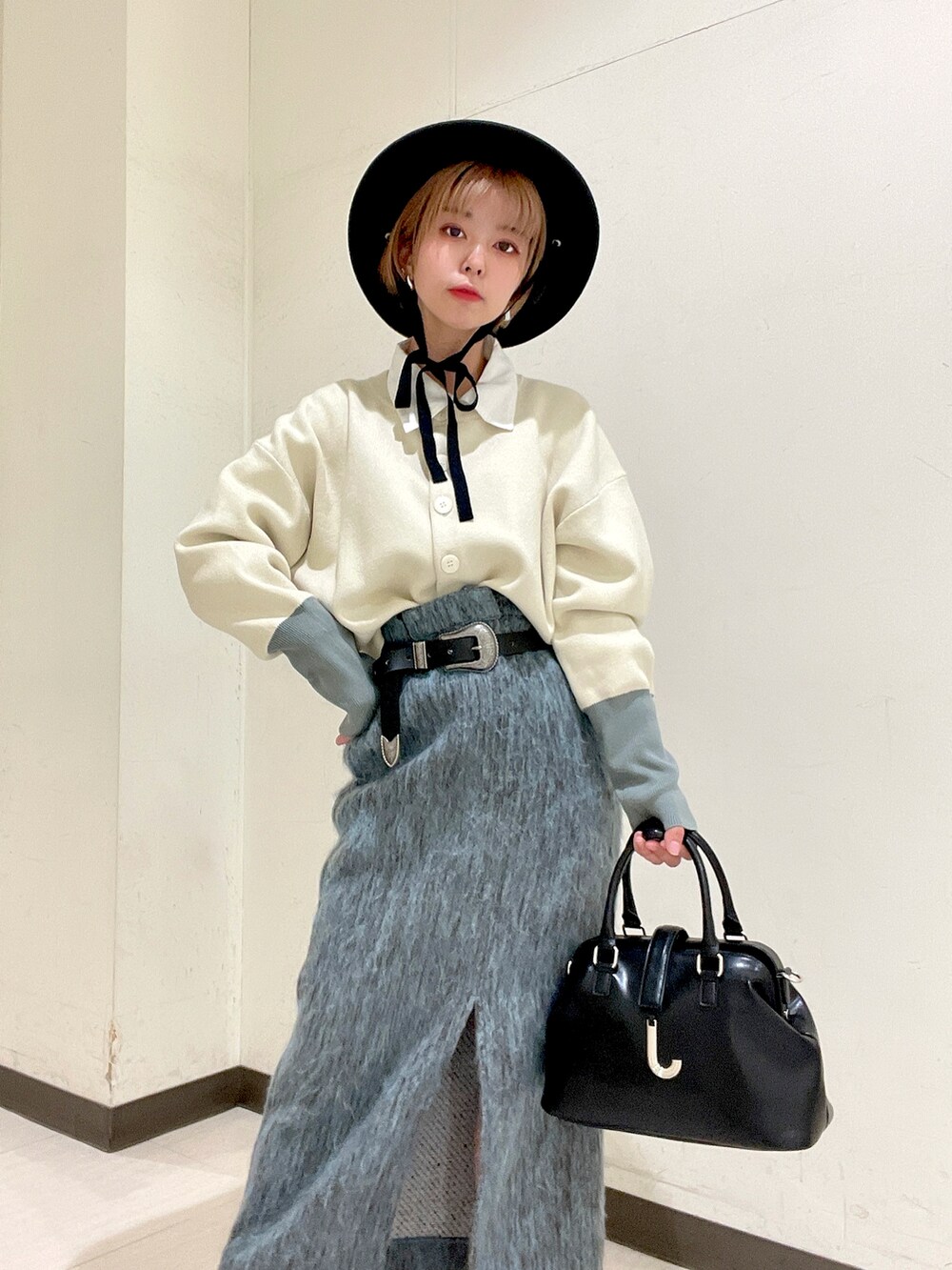 ホワイト系のカーディガン/ボレロ、ブルー系のスカート、ブラック系のパンプスを着用したレディースの冬コーディネートの3枚目の写真